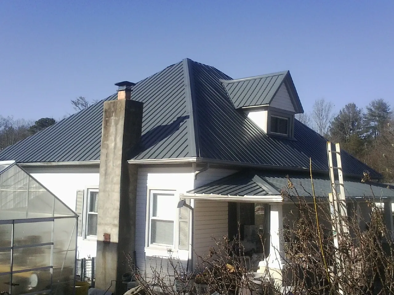 Dark blue standing seam metal roof on a white farmhouse with dormer — Slate & Tile Roof Repair by Roofing Brothers in Carnation