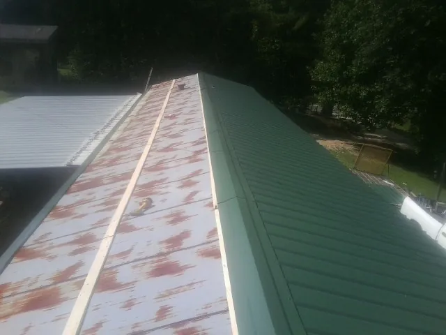 Old rusted panels beside newly installed green metal roofing — Wind Damage Roof Repair by Roofing Brothers in Carnation