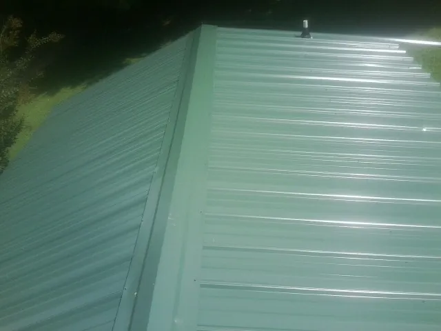 New green metal panels meeting at the ridge of a roof — Flat Roof Repair work by our crew in Carnation