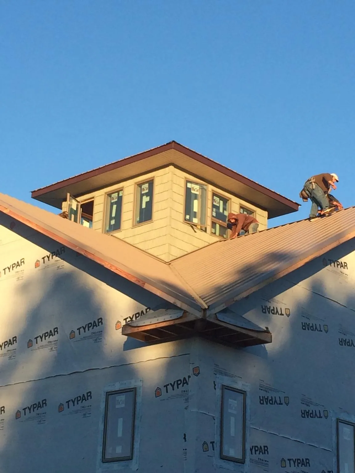 Roofers working around a rooftop cupola on a new metal roof at sunset — Roof Waterproofing in Carnation by Roofing Brothers